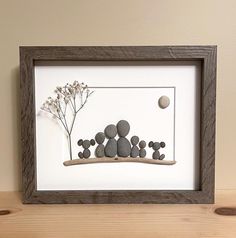 a wooden frame with rocks and flowers in it on a table next to a wall