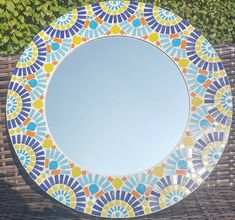 a round mirror sitting on top of a wooden table next to a plant covered wall