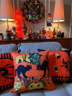 three halloween pillows sitting on top of a couch next to two lamps and a clock