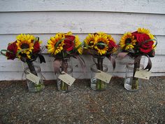 four vases with sunflowers and roses in them are sitting on the ground