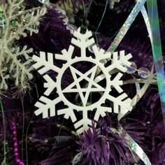 a white snowflake ornament sitting on top of a purple christmas tree