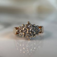 a diamond cluster ring sitting on top of a table