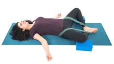 a woman laying on a yoga mat with her arms stretched out in the air while stretching