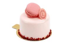 a white cake with pink frosting and two macaroons on top