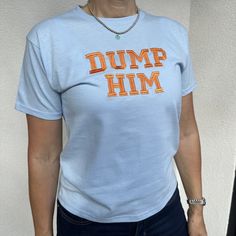 "Baby blue T shirt with orange spell out \"dump him\" embroidery  Remake of a T shirt worn by Britney Spears in y2k Sizing of T Shirt shown in photo 6. For reference, model is 5'5 with 31\" bust and 26\" waist" Blue Top With Embroidered Text For Streetwear, Y2k Fitted T-shirt With Custom Print, Dump Him, Blue Tops With Embroidered Text For Streetwear, Blue Embroidered Text Top For Streetwear, Blue Embroidered Text Streetwear Tops, Blue Embroidered College T-shirt, Dump Him Britney, 2000s Slogan Tees