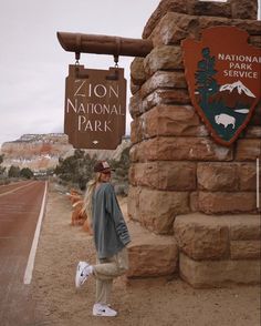 a woman standing in front of a sign for the national park