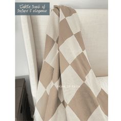 a white and brown checkered blanket sitting on top of a bed