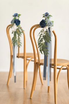 three wooden chairs with flowers on them and ribbons tied to the back of one chair