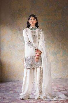 Pure White Raw Silk Salwar Kameez Pakistani Party Dresses come is a beautiful affair that enlivens a sensorial experience. The pure white fabric is featured in a classic long shirt, flared trousers, and organza dupatta. Kameez: An outstanding kameez in white comes in off-white and gold embroidery. A pure white fabric reminisces an angel look featured in a three-piece. A short white shirt with silver embellishments on the hem and sleeves. The fabric sued for this kameez is raw silk Salwar: Pakist Raw Silk Salwar, Pakistani Party Dresses, Salwar Kameez Pakistani, Pakistani Designer Clothes, Organza Sleeves, Luxe Wedding, Organza Dupatta, Embroidered Neckline, Organza Fabric