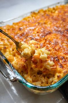 a casserole dish with macaroni and cheese being scooped from the casserole