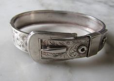 Bangle  Code AA1E A Beautiful  Sterling Silver Bangle in an engraved Buckle Design with a plain back  Width 1.2cms Wide - 6cms inside closed wide - I Have a 16.5cms wrist and it fits me just right  Approx 19gms  In Good Condition  Stamped  " Chester 1938 JH&S " Other Bracelets not included Formal Engraved Antique Silver Bracelet, Antique Engraved Sterling Silver Bracelet For Formal Events, Victorian Sterling Silver Bracelet, Engraved For Formal Occasions, Ornate Stamped Bracelets For Formal Occasions, Adjustable Engraved Bangle For Formal Occasions, Adjustable Engraved Bracelets For Formal Occasions, Antique Stamped Cuff Bracelet For Formal Occasions, Vintage Bangle Jewelry With Engraving Option, Antique Stamped Bracelets For Formal Occasions