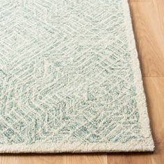 a light blue and white area rug on the floor with wood floors in the background