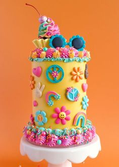 a brightly colored cake with buttons and decorations on it's side, against an orange background