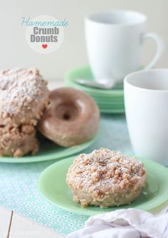 two donuts on green plates next to cups and saucers