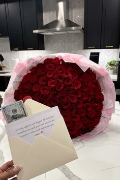 a bouquet of red roses and an envelope are on the counter in front of a stove