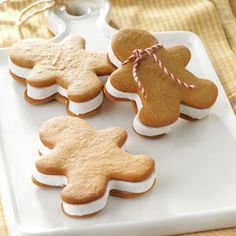 four gingerbread cut out cookies on a white platter with twine and string