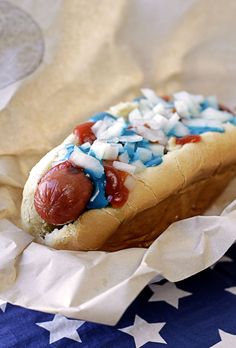 a hot dog with condiments on it sitting on top of an american flag napkin