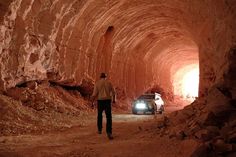 a man standing in the middle of a tunnel next to a car with headlights on