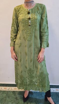 Soft and Rich Muslin Silk Kurta with ruffle at the hem and sleeves. Delicately embroidered in chikankari with self threadwork. Side slits for comfort. Full sleeves. Handmade tassels. Length - 49 inches Color - Olive Green Size -  S - fits bust 34 M - fits bust 36 L - fits bust 38 XL - fits bust 40 0X - fits bust 42 1X - fits bust 44 2X - fits bust 46 Spring Green Tunic With Chikankari Embroidery, Green Bohemian Embroidered Dress With Chikankari, Green Bohemian Dress With Chikankari Embroidery, Green Chikankari Embroidery Tunic For Spring, Cotton Embroidered Dress With Chikankari For Eid, Green Chikankari Embroidered Tunic For Spring, Spring Cotton Kurta With Tonal Embroidery, Spring Bohemian Kurta With Cutwork, Spring Long Sleeve Kurta With Tonal Embroidery