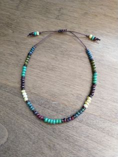 a necklace with multi colored beads on a wooden table