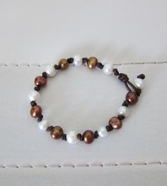 This bracelet has 7mm round brown & white freshwater pearls hand knotted on dark brown leather.   Clasp is another pearl with loop.   Looks great worn on it's own or stacked with other bracelets from my shop for a truly Boho look! Brown Leather Bracelet With Round Beads, Brown Hand-strung Leather Bracelet Gift, Hand-strung Brown Leather Bracelet Gift, Adjustable Hand-strung Brown Leather Bracelet, Elegant Adjustable Brown Pearl Bracelet, Peacock Pearl, Biwa Pearls, Black Leather Bracelet, White Bracelets