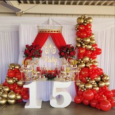 a table with red and gold balloons in the shape of christmas trees, surrounded by decorations