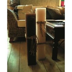 three candles sitting on top of a wooden floor next to a couch and coffee table