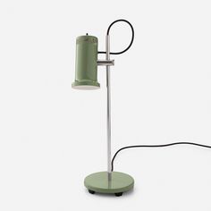 a green table lamp sitting on top of a white floor next to a black cord