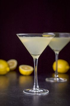 two martini glasses with lemons in the background