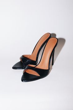 The sexiest stilettos you'll ever own! Gia is a minimal mule that will garner all the attention. Glossy Black Vegan Leather with a faux reptile texture. Size and Fit Information: U.S. Sizing Available in whole and half sizes Runs true to size (Some customers have sized up a half size since back is open) (Note: Not using leather and other materials from animals significantly reduces environmental impact, however, we acknowledge that synthetic alternatives are not without environmental concerns. A Sleek Mules With 4-inch Heel For Night Out, Sleek High Heel Mules For Night Out, Luxury High Heel Mules For Night Out, Luxury Mules With 4-inch Heel For Night Out, Classic Black Synthetic Mules, Sleek Black Mules With Single Strap, Sleek Black Leather Mules, Snake Print Heels With Pointed Toe For Evening, Evening Heels With Snake Print And Pointed Toe