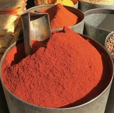 several buckets filled with different types of red powder and beans, including lentils