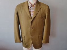 50's Ivy Style Sport Coat. Single breasted, 3 button closure with notched lapels, flap patch side pockets, welted chest pocket. Single vent. Half lined in nylon satin with single interior billfold pocket. Twill weave wool-linen in golden moss color. By Club Clothes. In exceptional condition with no discernible flaws. Measures: 40" Chest 24" Sleeves (shoulder edge to cuff) 19" Shoulder to shoulder 31" Length (rear collar to hem)  This item is pre-owned, true vintage. Images, description, and measurements are as accurate a representation of this item as is possible. Color may vary slightly due to lighting or individual monitor calibration. This item is stored and shipped from a smoke/pet-free environment and delivered clean and ready for use. **Please note: refunds are only offered for items Single Breasted Button-up Suit For Fall, Semi-formal Spring Tweed Jacket With Pockets, Spring Semi-formal Tweed Jacket With Pockets, Semi-formal Fall Suits With Pockets, Formal Button-up Tweed Jacket With Pockets, Fall Suits With Welt Pockets And Flat Front, Classic Solid Color Collared Blazer, Button-up Suits With Pockets For Fall, Fall Semi-formal Button-up Sport Coat