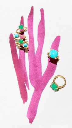 three rings sitting on top of a pink piece of paper next to a pair of turquoise stones