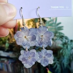 a pair of earrings with flowers hanging from it's earwires in front of a card