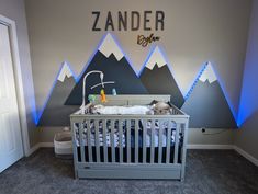 a baby's room with mountains on the wall and a crib in it