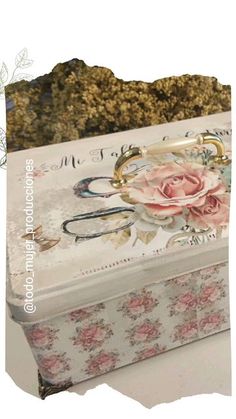 a white box with pink flowers on it sitting on top of a table next to a pile of dirt