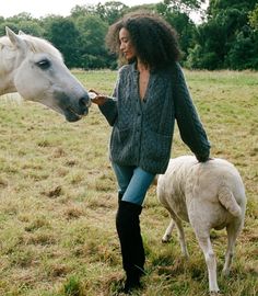 a woman is petting a horse and sheep