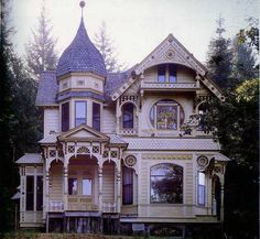 an old victorian style house with a turret on the top floor and two stories, in front of some trees