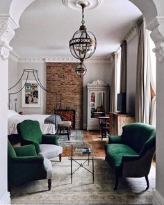 a living room filled with furniture and a chandelier hanging over it's fireplace