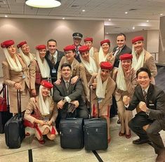 a group of men and women posing for a photo in an airport with their luggage