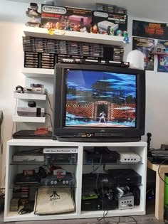 a television sitting on top of a white entertainment center next to a wall filled with video games