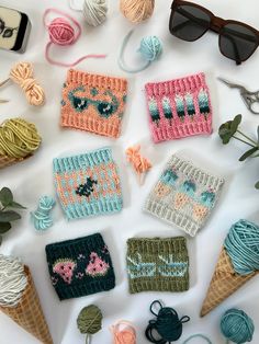 crocheted items are laid out on a table with yarn, sunglasses and knitting needles