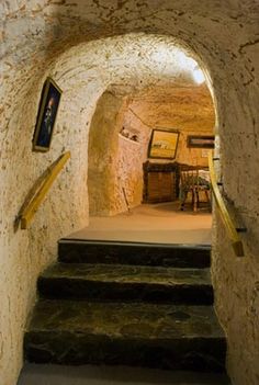 an old stone tunnel with stairs leading up to the kitchen and dining room table on either side