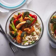 two glass bowls filled with rice, broccoli and chicken on top of a table