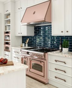 a pink stove top oven sitting inside of a kitchen next to white cabinets and drawers