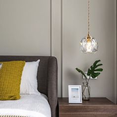 a bedroom with a bed, night stand and lamp hanging from the ceiling above it