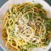 a white plate topped with pasta and broccoli covered in cheese on top of it