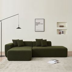 a large green couch sitting on top of a white rug next to a floor lamp