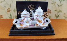 a porcelain tea set with matching saucers on a tray