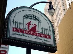 the sign for pitty pat's porch southern dining in front of tall buildings